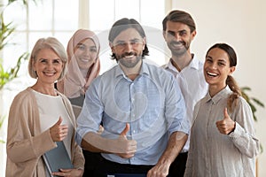 Group portrait of smiling multiethnic employees colleagues showing thumbs up