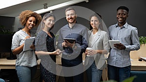 Group portrait of smiling multiethnic team posing in office