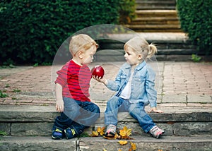 Group portrait of two white Caucasian cute adorable funny children toddlers sitting together sharing apple food