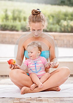 Group portrait of white Caucasian mother and baby daughter doing physical fitness exercises yoga together sitting in lotus pose on