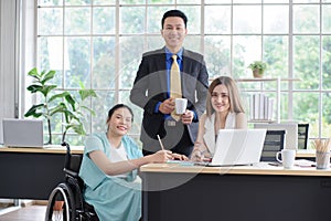 Group portrait of young Asian disabled working woman with her colleagues, businessman and businesswoman