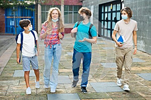 Group of positive cheerful teenagers hanging out on streets of city on day