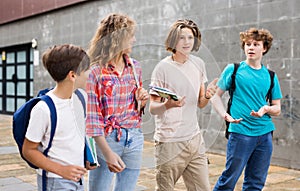 Group of positive cheerful teenagers hanging out on streets of city on day