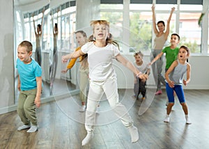 Group of positive juvenile boys and girls jumping cheerfully in dancehall