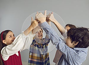 Group of positive little children give thumbs up as they join their hands together
