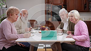 Group of positive senior men and women chatting online using video chat on digital tablet on tea party. Smiling