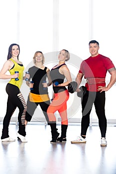 Group of positive sporty bodybuilders doing weight training in g