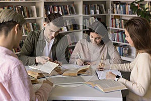 Group of positive young hardworking smart students studying in library