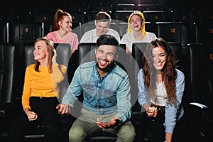 A group of positive young people laughing, watching a movie at the cinema