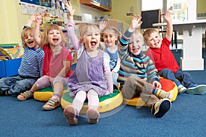 Group Of Pre School Children Answering Question In Classroom