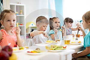 Group of preschool kids have a lunch in daycare. Children eating healthy food in kindergarten