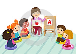 Group of preschool kids and teacher sitting on the floor.Teacher explaining alphabet to children photo