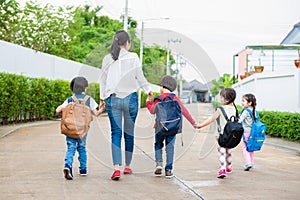 Group of preschool student and teacher holding hands and walking