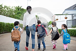 Group of preschool student and teacher holding hands and walking to home. Mom bring her children go to school together. Back to