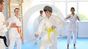 Group of preteen children in kimono trying new martial moves at karate class