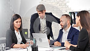 Group of professional colleague brainstorming discussing project with male teamleader using laptop