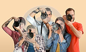 Group of professional photographers with cameras on beige background