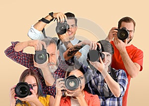 Group of professional photographers with cameras on beige background