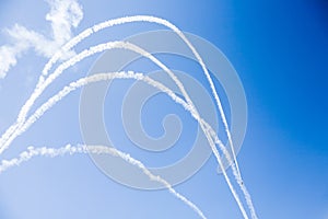 A group of professional pilots of military aircraft of fighters on a sunny clear day shows tricks in the blue sky, leaving beauti