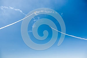 A group of professional pilots of military aircraft of fighters on a sunny clear day shows tricks in the blue sky, leaving beautif