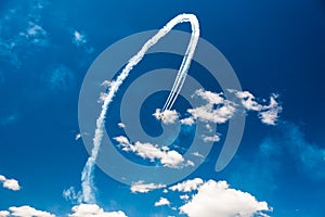 A group of professional pilots of military aircraft of fighters on a sunny clear day shows tricks in the blue sky, leaving beauti