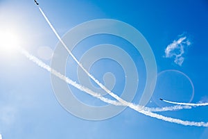 A group of professional pilots of military aircraft of fighters on a sunny clear day shows tricks in the blue sky, leaving beauti