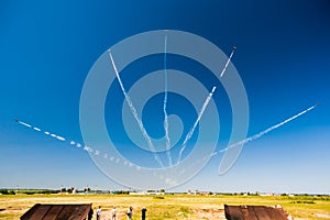 A group of professional pilots of military aircraft of fighters on a sunny clear day shows tricks in the blue sky, leaving beauti