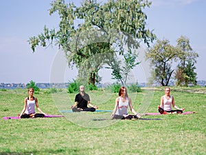 A group of professional yogis meditate in the city park.