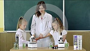 Group Of Pupils With Teacher Using Microscopes In Science Class. chalkboard on background, copy space. Back to school and home