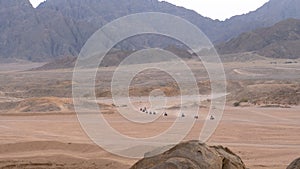 Group on Quad Bike Rides through the Desert in Egypt on backdrop of Mountains. Driving ATVs.