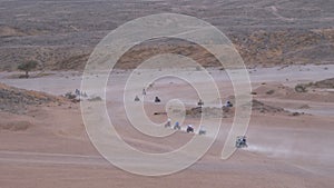 Group on Quad Bike Rides through the Desert in Egypt on backdrop of Mountains. Driving ATVs.