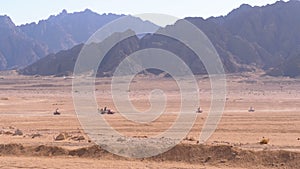 Group on Quad Bike Rides through the Desert in Egypt on backdrop of Mountains. Driving ATVs.