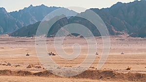 Group on Quad Bike Rides through the Desert in Egypt on backdrop of Mountains. Driving ATVs.