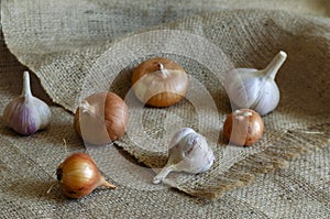 A group of raw brown onion and garlic bulbs on the sack