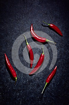 Group of red hot spicy vegetables. High angle view of chilli peppers on dark blue background. Spicy ingredients in kitchen