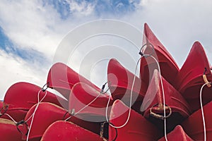 group of red kayaks piled up against each other on the shore seen from below