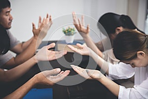 Group of religious people praying together indoors. group of people holding hands and praying while sitting in office