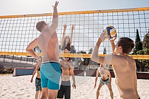 Group of resting playing volleyball on beach court