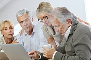 Group of retired people at home using laptop