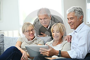 Group of retired people sitting in sofa with tablet