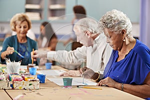 Group Of Retired Seniors Attending Art Class In Community Centre With Teacher