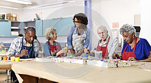 Group Of Retired Seniors Attending Art Class In Community Centre With Teacher