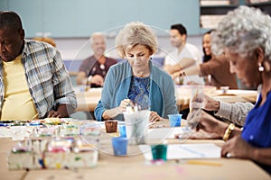 Group Of Retired Seniors Attending Art Class In Community Centre With Teacher