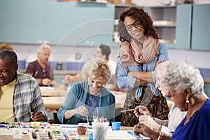 Group Of Retired Seniors Attending Art Class In Community Centre With Teacher