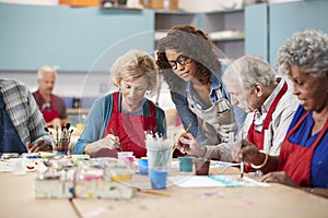 Group Of Retired Seniors Attending Art Class In Community Centre With Teacher