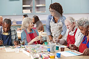 Group Of Retired Seniors Attending Art Class In Community Centre With Teacher