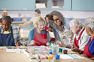 Group Of Retired Seniors Attending Art Class In Community Centre With Teacher