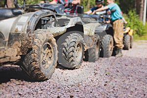 Group of riders riding ATV vehicle crossing forest rural road, process of driving rental vehicle, all terrain quad bike vehicle,