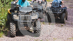 Group of riders riding ATV vehicle crossing forest rural road, process of driving rental vehicle, all terrain quad bike vehicle,