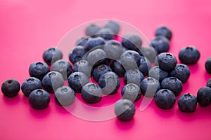 Group of ripe and juicy blue on a color pink background, close-up of berries, selective focus